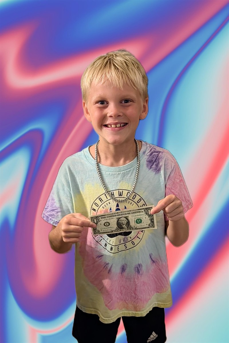 Jude smiling and holding up the first dollar he earned from JudeMade